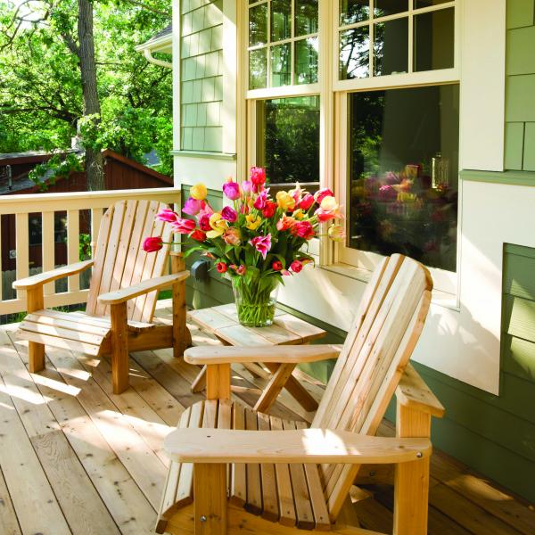 Photo of a residential deck with two deck chairs and flowers.