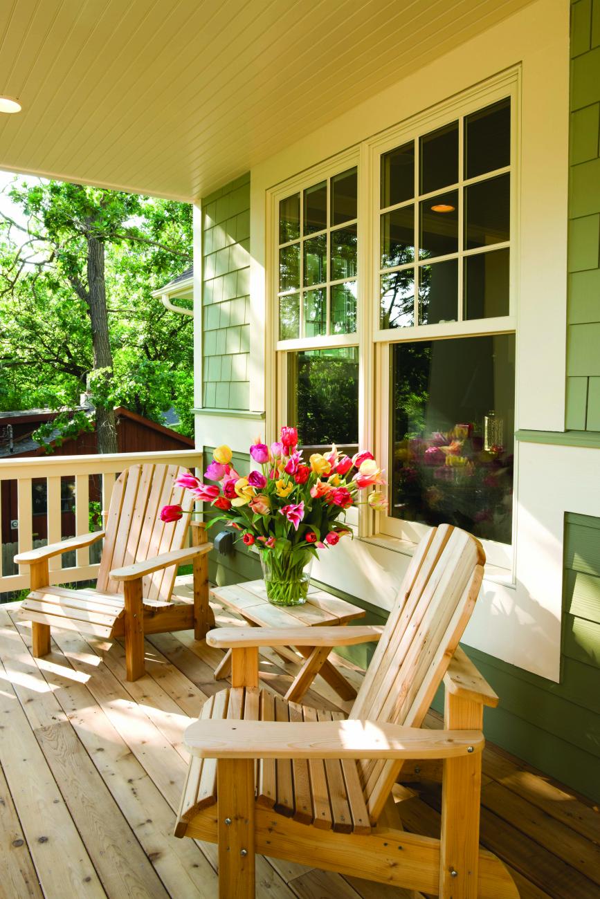 Photo of a residential deck with two deck chairs and flowers.